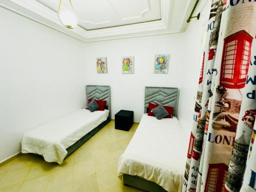 two beds in a room with white walls at spacieuse vacation appartements in Essaouira