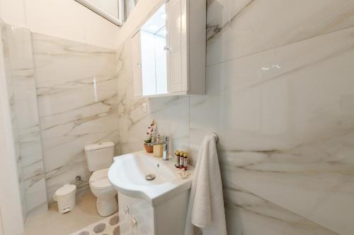 a white bathroom with a sink and a toilet at Venetian Balcony , Old Town Corfu in Corfu