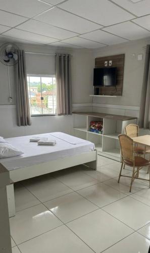a bedroom with a large bed and a table and chairs at Hotel Hallas in Betim