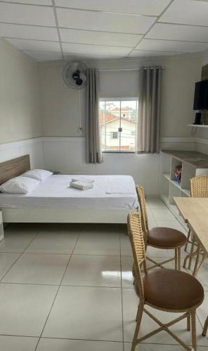 a bedroom with a bed and two chairs and a window at Hotel Hallas in Betim