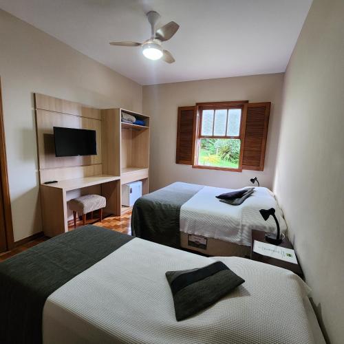 a hotel room with two beds and a television at Casa Antunes in Diamantina