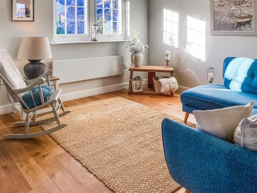 a living room with a blue couch and a chair at Seascape in Garlieston