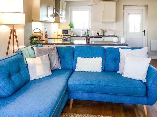 a blue couch with white pillows in a kitchen at Seascape in Garlieston