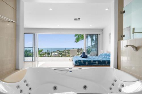 a large white bath tub in a room with a large window at Acqua Vista in Terrigal