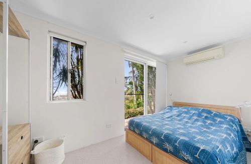a bedroom with a bed and two windows at Acqua Vista in Terrigal