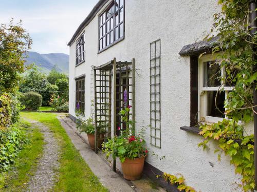 a white house with potted plants on the side of it at Jemima's Cottage in Bassenthwaite