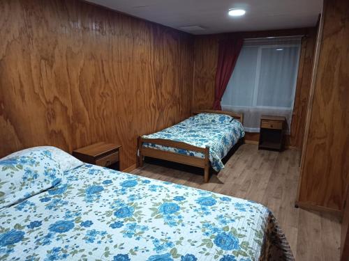 two beds in a room with wooden walls at Casa Cardenal in Castro