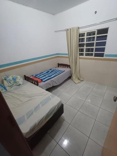 two beds in a room with a window at Casa moto gp in Goiânia