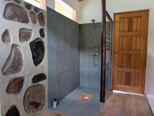 a bathroom with a shower with a stone wall at Mana Henua Lodge in Nuku Hiva