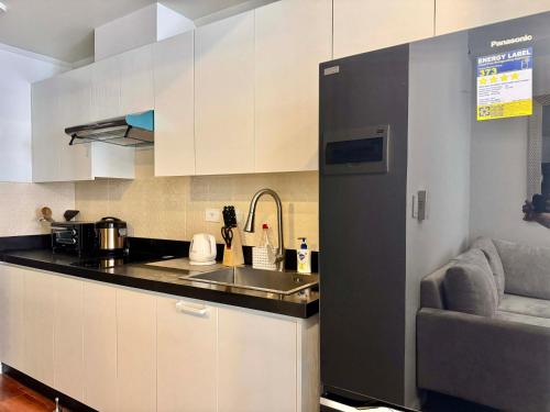 a kitchen with white cabinets and a sink and a couch at Ivory Davao Condotel near DMSF in Davao City
