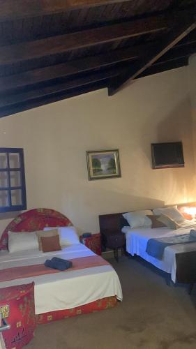 a bedroom with two beds and a tv on the wall at Quinta Arce - Refugio Natural in Trinidad