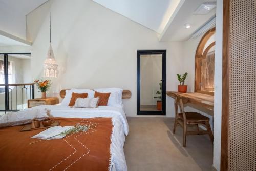 a bedroom with a large bed and a desk at Casa pumara loft in Kerobokan