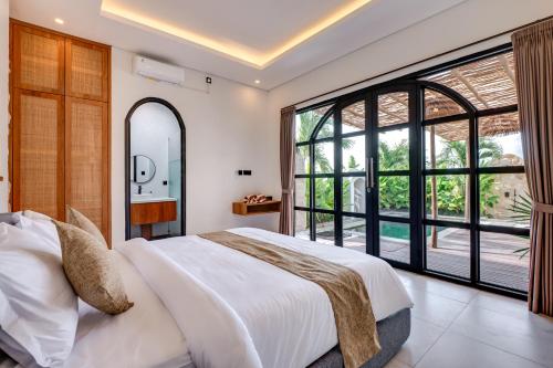 a bedroom with a large bed and a large window at Tresna Villa Tumbak Bayuh Utara in Dalung
