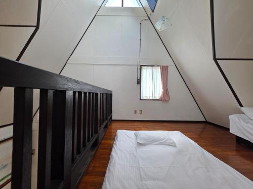 a attic room with a bed and a window at LOGIN OKINAWA -mayonaka- in Onna