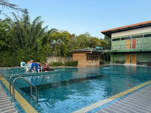 two people sitting in chairs by a swimming pool at Keeree at chiewlarn in Ban Tha Khun