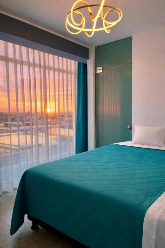 a bedroom with a green bed and a large window at LAS GAVIOTAS DE PARACAS in Paracas