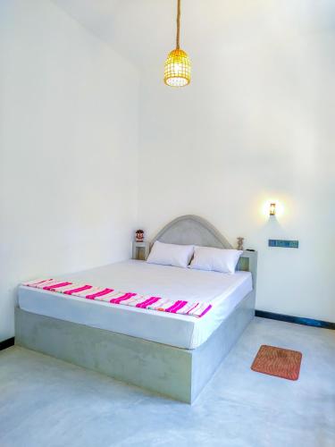 a white bedroom with a bed with pink and white pillows at YK House Midigama in Midigama East