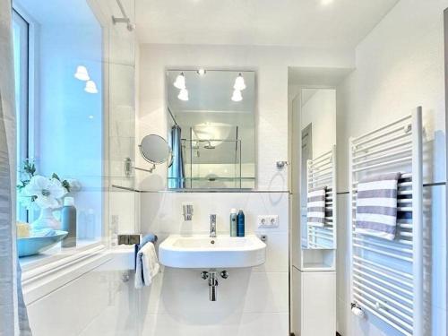 a white bathroom with a sink and a mirror at Schroeders-Haus-Mitte in Kampen