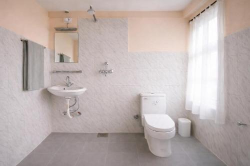 a white bathroom with a toilet and a sink at Funky Monkey Hostel Hotel & Apartment Thamel in Kathmandu