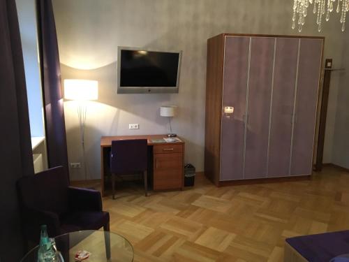 ein Wohnzimmer mit einem Schreibtisch und einem TV sowie ein Zimmer in der Unterkunft Hotel Schloss Rabenstein in Chemnitz