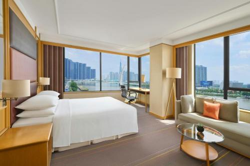 a hotel room with a white bed and a couch at Renaissance Riverside Hotel Saigon in Ho Chi Minh City