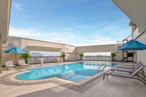 a pool at a hotel with chairs and umbrellas at Renaissance Riverside Hotel Saigon in Ho Chi Minh City