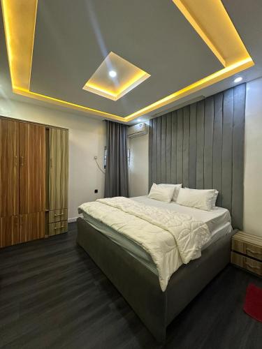a bedroom with a large bed with a ceiling at EIMACK APARTMENT Service in Asaba