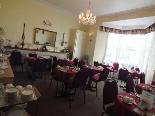 a dining room with tables and chairs and a chandelier at Taormina Guest House in Tenby