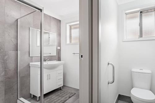 a white bathroom with a toilet and a sink at Barefoot Bungalow in Nelson Bay