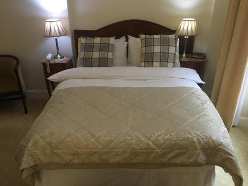 a bedroom with a large bed with two lamps at Mansfield House Hotel in Hawick