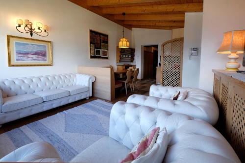 - un salon avec deux canapés blancs et une table dans l'établissement Residenza Bagni & Miramonti, à Cavalese