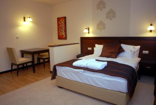 a bedroom with a bed and a desk and a table at Hotel Aurum in Hajdúszoboszló