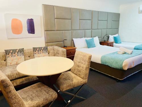 a hotel room with two beds and a table and chairs at Kinross Inn in Cooma