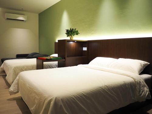 a bedroom with two beds and a green wall at Roxy Beach Apartment, Sematan, Sarawak in Sematan