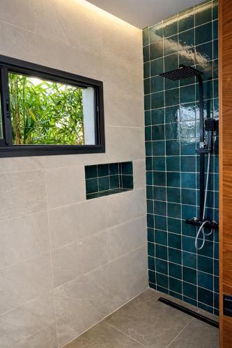 a bathroom with a shower with blue tiles and a window at Villa de luxe piscine chauffée & Jacuzzi & Petit déjeuner in Fez