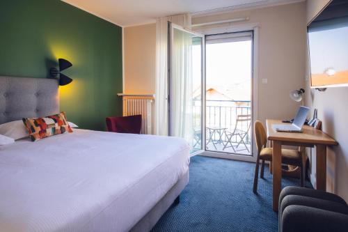 a bedroom with a bed and a desk with a laptop at Cit'Hotel Logis De Brou, Bourg en Bresse RENOVE EN 2026 in Bourg-en-Bresse