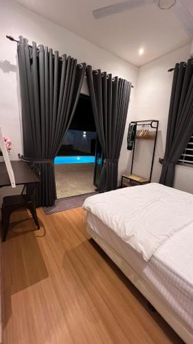 a bedroom with black curtains and a bed and a desk at Serene Private Villa Kangar in Kangar