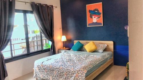 a bedroom with a bed with blue walls and a window at SpamHouse Ranong in Ban Bang Rin (1)