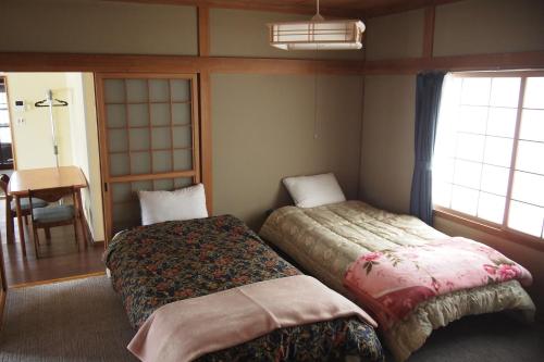 a bedroom with two beds and a table and a window at Puffin House in Engaru