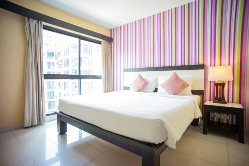 a bedroom with a large bed and a window at Neo Hotel Pattaya in Jomtien Beach