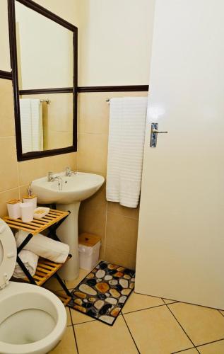 a bathroom with a white toilet and a sink at Cozy Comfortable Apartment with pool in Pretoria