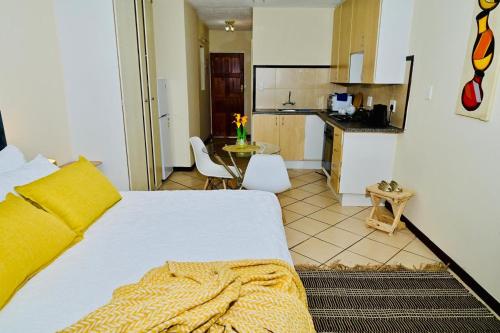 a bedroom with a white bed and a kitchen at Cozy Comfortable Apartment with pool in Pretoria