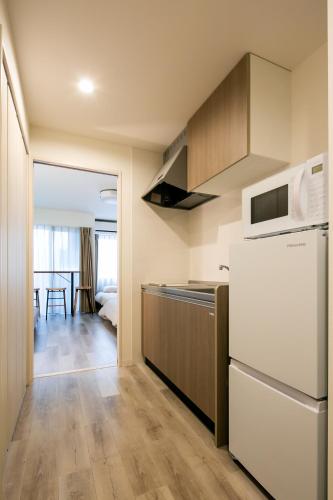 a kitchen with a refrigerator and a microwave at trive meieki nishi 105 最大6名宿泊可 名古屋駅まで1駅 太閤通駅徒歩4分 in Nagoya