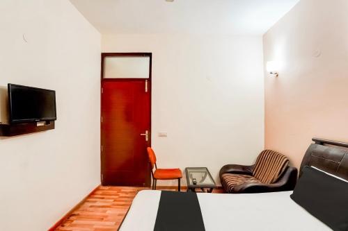 a bedroom with a bed and two chairs and a tv at Hotel O Le Regent in Gurgaon