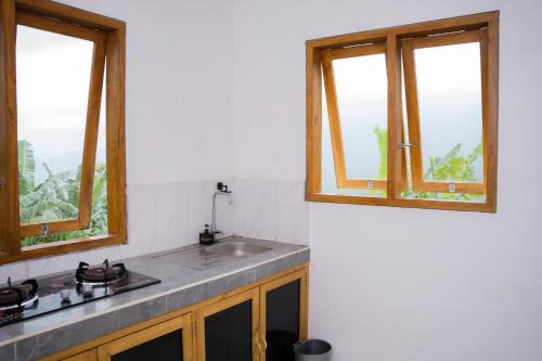 a kitchen with a sink and two windows at Melaka Hill in Culik