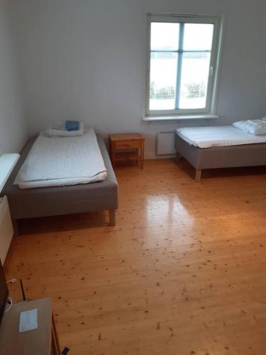 a room with two beds and a wooden floor at Workers Stay - Furnished Housing Umeå Sweden in Klabböle