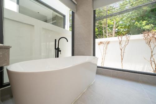 a white tub in a bathroom with a window at lucky pool villas in Phuket