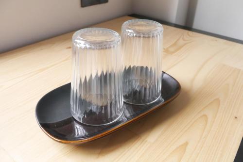 deux vases en verre sur une plaque noire sur une table en bois dans l'établissement Baan Mai Guest House, à Bangkok