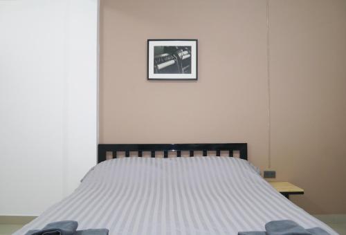 a bed in a bedroom with a picture on the wall at Baan Mai Guest House in Bangkok