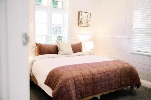 a bedroom with a bed with a blanket and a window at Maison Macquarie in Dubbo
